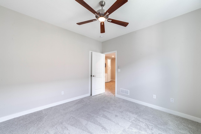carpeted spare room with visible vents, baseboards, and a ceiling fan