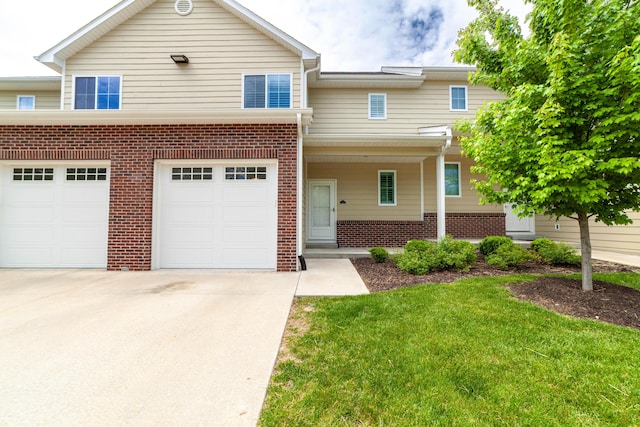 view of front of house featuring concrete driveway, an attached garage, a front lawn, and brick siding