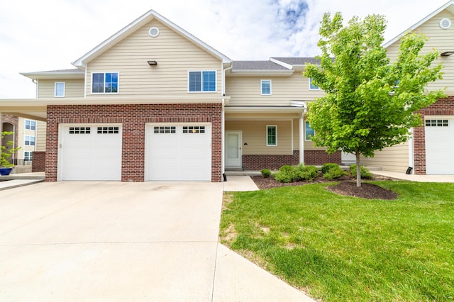 view of front of property featuring a front lawn, driveway, brick siding, and an attached garage