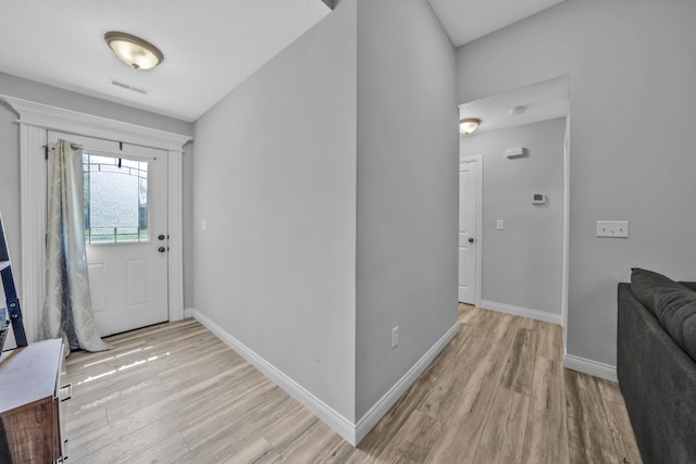 foyer with baseboards, visible vents, and light wood-type flooring