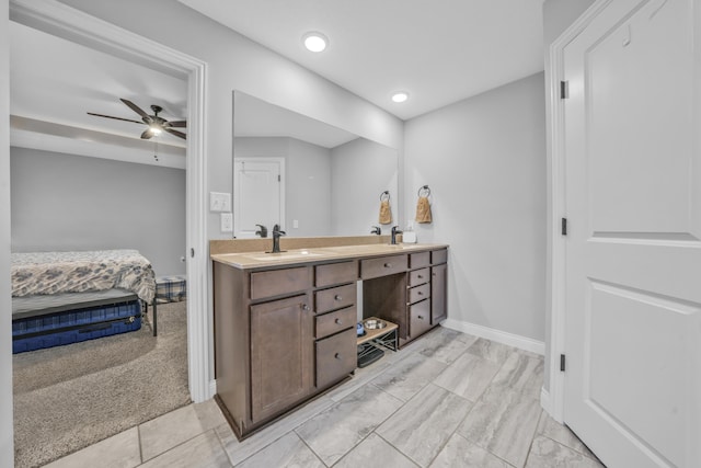 ensuite bathroom with connected bathroom, ceiling fan, a sink, double vanity, and baseboards