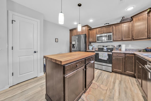 kitchen with butcher block countertops, light wood-type flooring, pendant lighting, and stainless steel appliances
