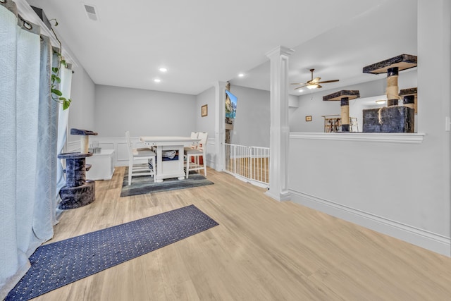 interior space featuring a ceiling fan, visible vents, wood finished floors, recessed lighting, and ornate columns