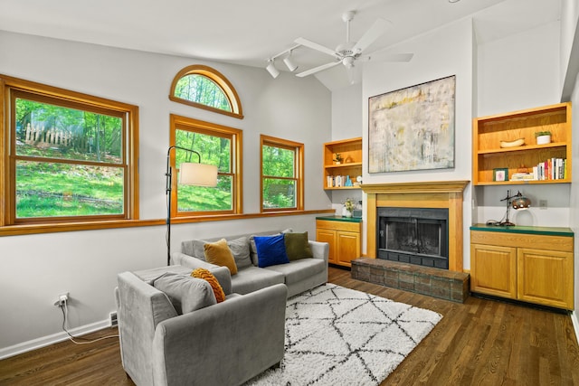 living area with ceiling fan, vaulted ceiling, dark wood-style floors, and a brick fireplace