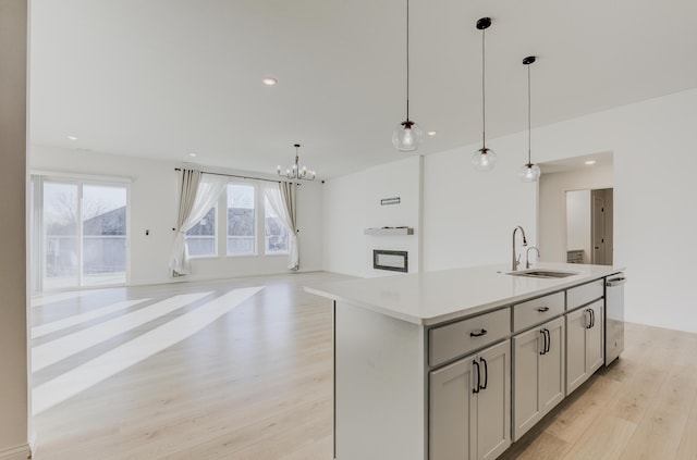 820 Angels Rest Way, Columbia, MO 65203 - kitchen featuring stainless steel dishwasher, a sink, light wood finished floors, a notable chandelier, and decorative light fixtures