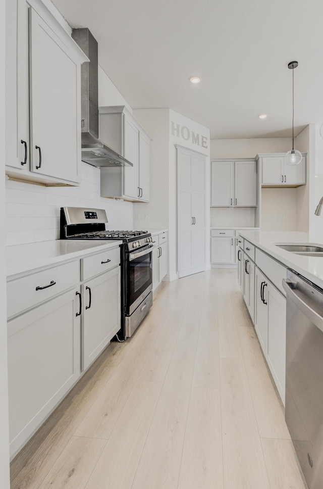 820 Angels Rest Way, Columbia, MO 65203 - kitchen featuring wall chimney range hood, a sink, light wood finished floors, hanging light fixtures, and stainless steel appliances