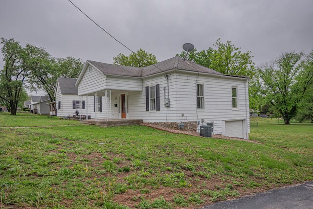 view of front of property featuring an attached garage, central AC, and a front yard