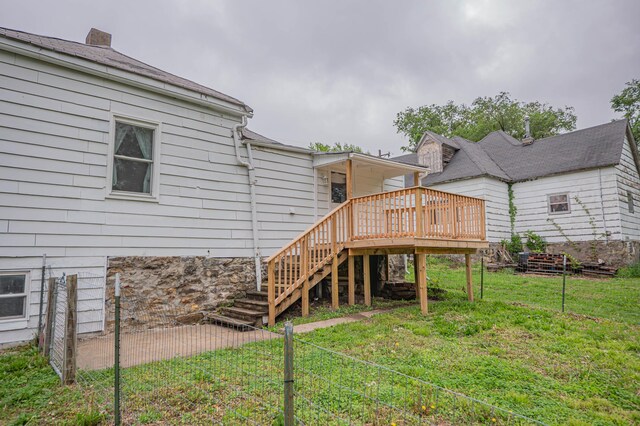 rear view of property with stairway, a lawn, fence, and a wooden deck