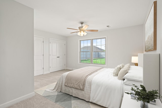 bedroom featuring a ceiling fan, visible vents, baseboards, carpet floors, and multiple closets