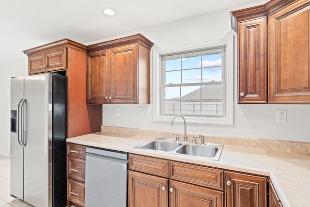 kitchen featuring light countertops, stainless steel appliances, brown cabinets, and a sink