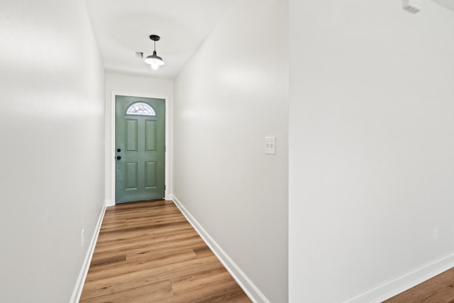 doorway with baseboards and light wood-type flooring