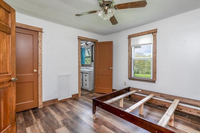 5435 N Creasy Springs Rd, Columbia, MO 65202 - unfurnished bedroom featuring baseboards, connected bathroom, ceiling fan, and wood finished floors