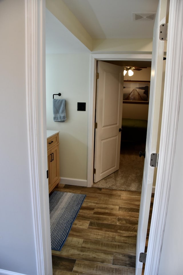 bathroom featuring ceiling fan, vanity, baseboards, wood finished floors, and visible vents