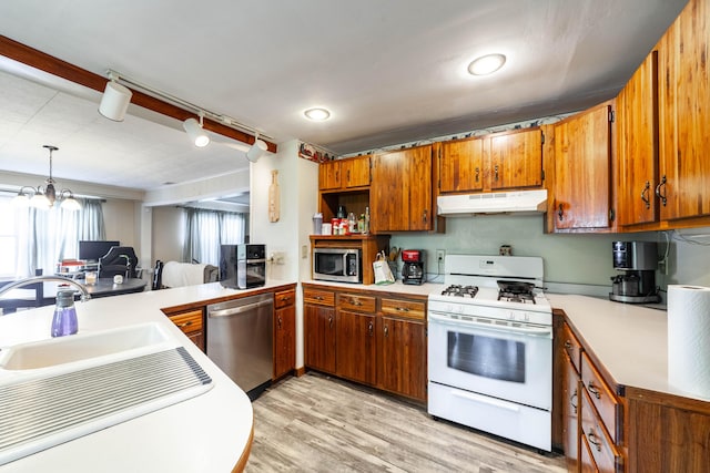 207 Lucky St, Fayette, MO 65248 - kitchen with stainless steel appliances, under cabinet range hood, brown cabinetry, a sink, and light countertops