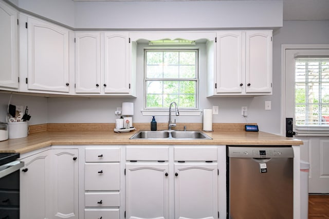 kitchen featuring a sink, stainless steel dishwasher, white cabinetry, and light countertops