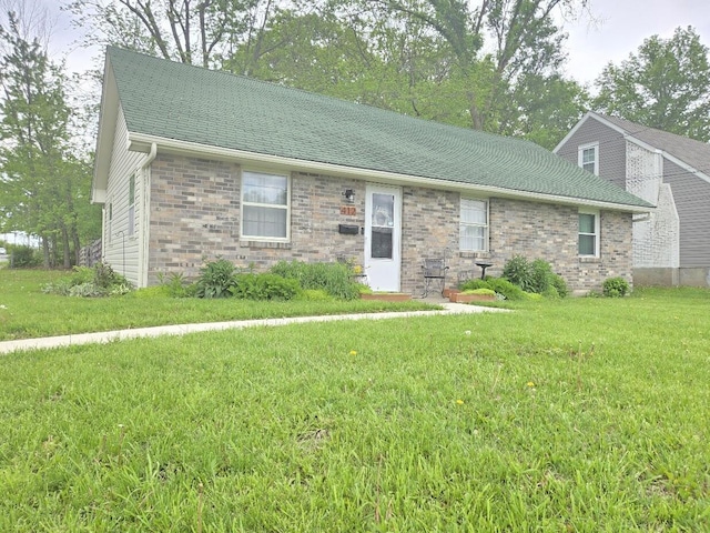 ranch-style home featuring a shingled roof, a front lawn, and brick siding