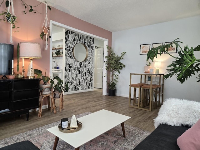 living room with baseboards, a textured ceiling, and wood finished floors