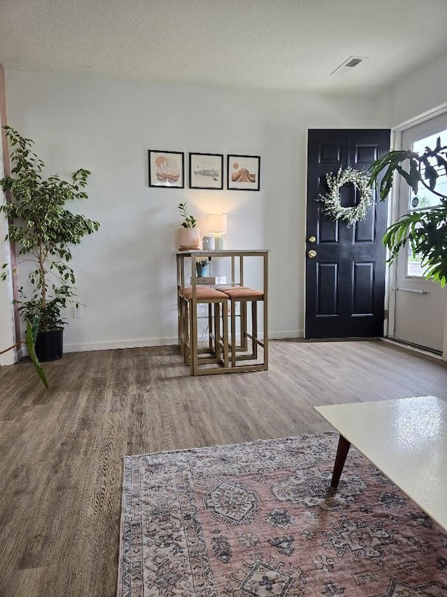 entrance foyer with baseboards, wood finished floors, and visible vents