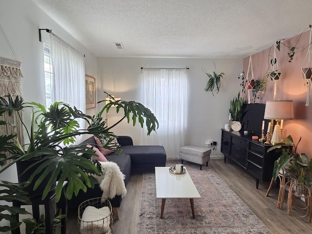 living room featuring a textured ceiling, visible vents, and wood finished floors