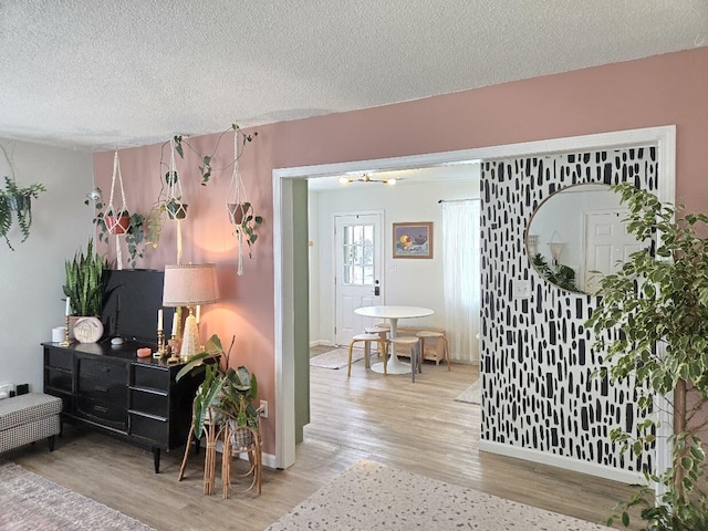 interior space featuring a textured ceiling, baseboards, and light wood-style flooring