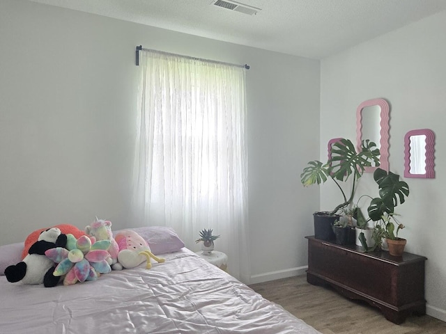 bedroom featuring baseboards, visible vents, and light wood finished floors