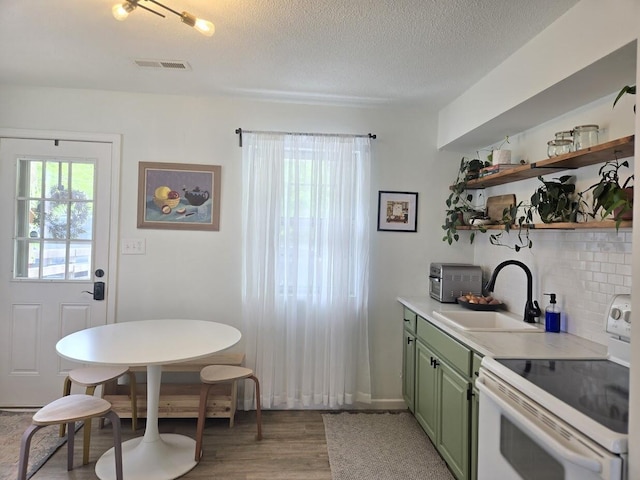 kitchen with a sink, light wood-style floors, visible vents, green cabinets, and white electric range