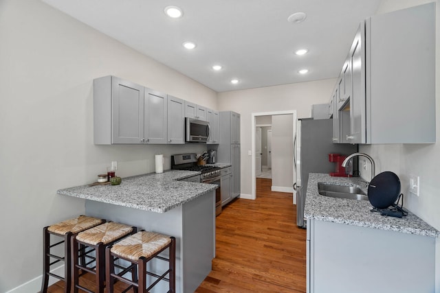 4520 County Road 1245, Moberly, MO 65270 - kitchen with appliances with stainless steel finishes, a kitchen breakfast bar, light wood-style flooring, recessed lighting, and baseboards
