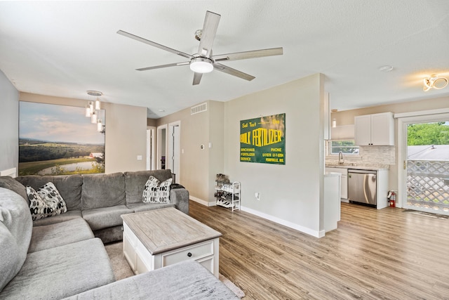 living room featuring light wood-style floors, ceiling fan, and baseboards