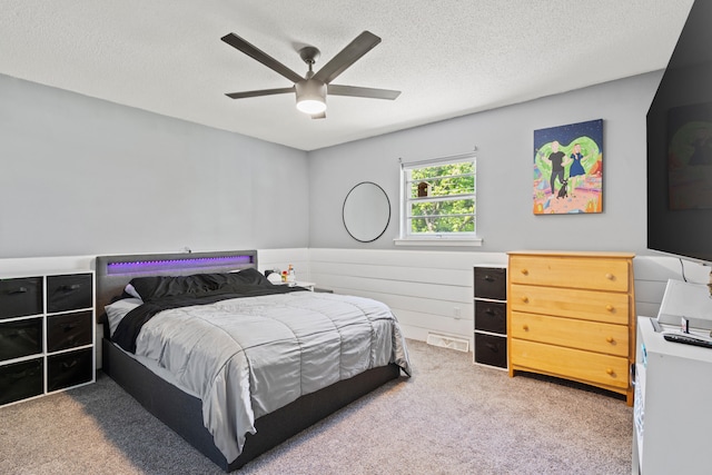 bedroom with light colored carpet, a textured ceiling, and a ceiling fan