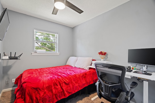 carpeted bedroom with a textured ceiling, a desk, ceiling fan, and baseboards