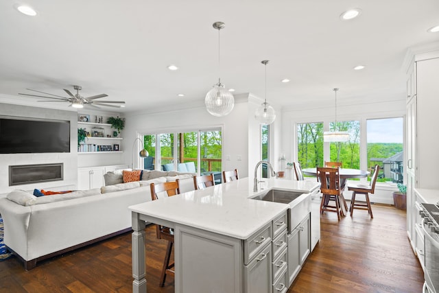 kitchen featuring a sink, a breakfast bar, crown molding, an island with sink, and recessed lighting