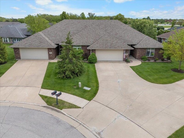 single story home featuring concrete driveway, a front lawn, brick siding, and an attached garage