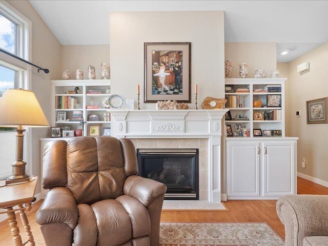 living room featuring light wood finished floors, a fireplace, and baseboards