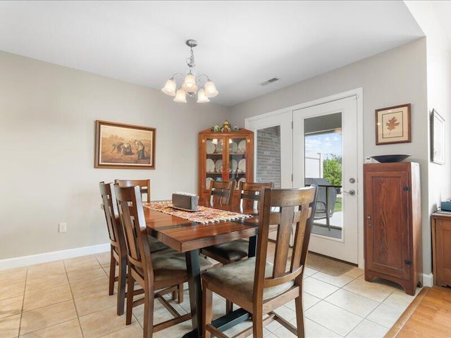 dining room with an inviting chandelier, light tile patterned floors, visible vents, and baseboards
