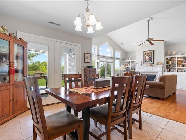 dining room with light tile patterned floors, a healthy amount of sunlight, a fireplace, and visible vents