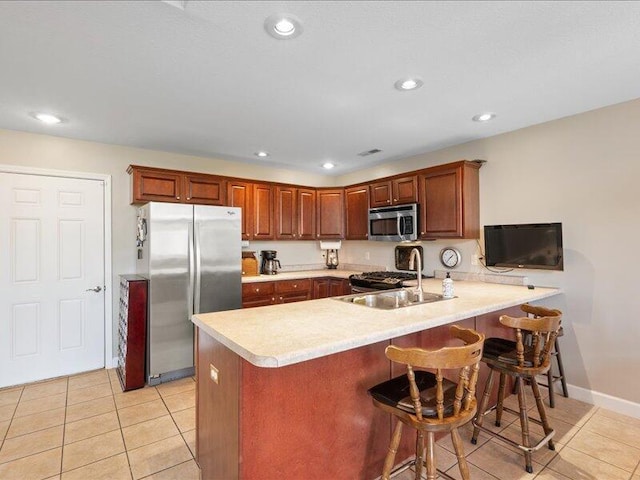 kitchen featuring light countertops, a peninsula, appliances with stainless steel finishes, and light tile patterned flooring