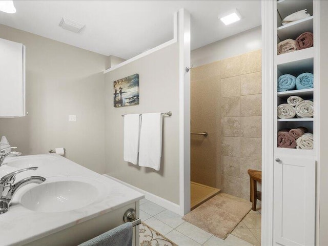 bathroom featuring a sink, a tile shower, double vanity, and tile patterned floors