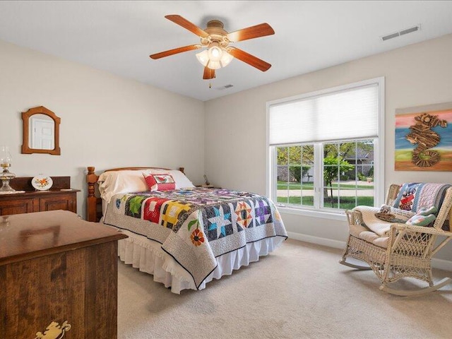 bedroom with visible vents, a ceiling fan, and light carpet