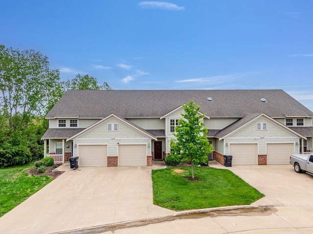 craftsman-style home with a front lawn, a shingled roof, brick siding, and driveway