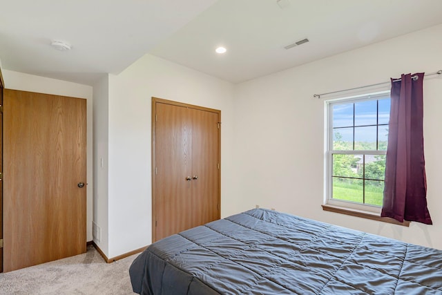 bedroom with a closet, visible vents, recessed lighting, light carpet, and baseboards