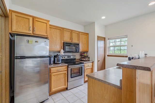 kitchen featuring light tile patterned floors, dark countertops, stainless steel appliances, and recessed lighting