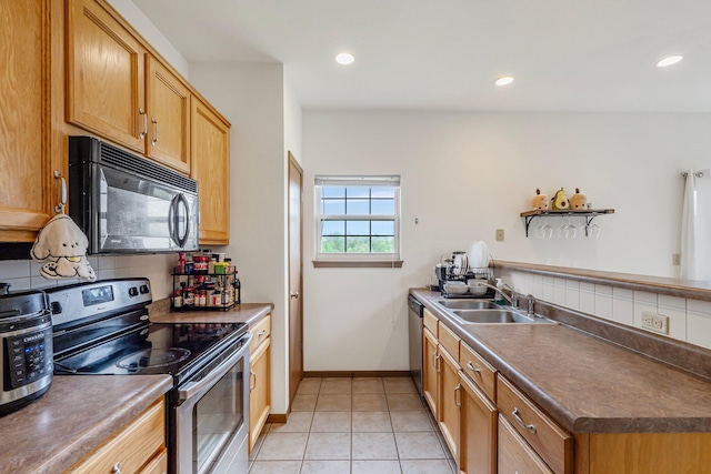 kitchen featuring a sink, a peninsula, stainless steel appliances, tasteful backsplash, and light tile patterned floors
