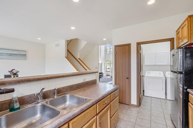 kitchen featuring washer and dryer, a sink, freestanding refrigerator, dark countertops, and light tile patterned flooring