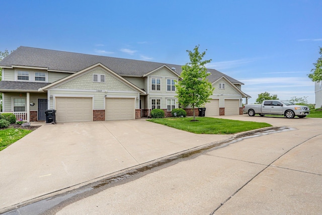 view of property with concrete driveway, a front yard, and brick siding