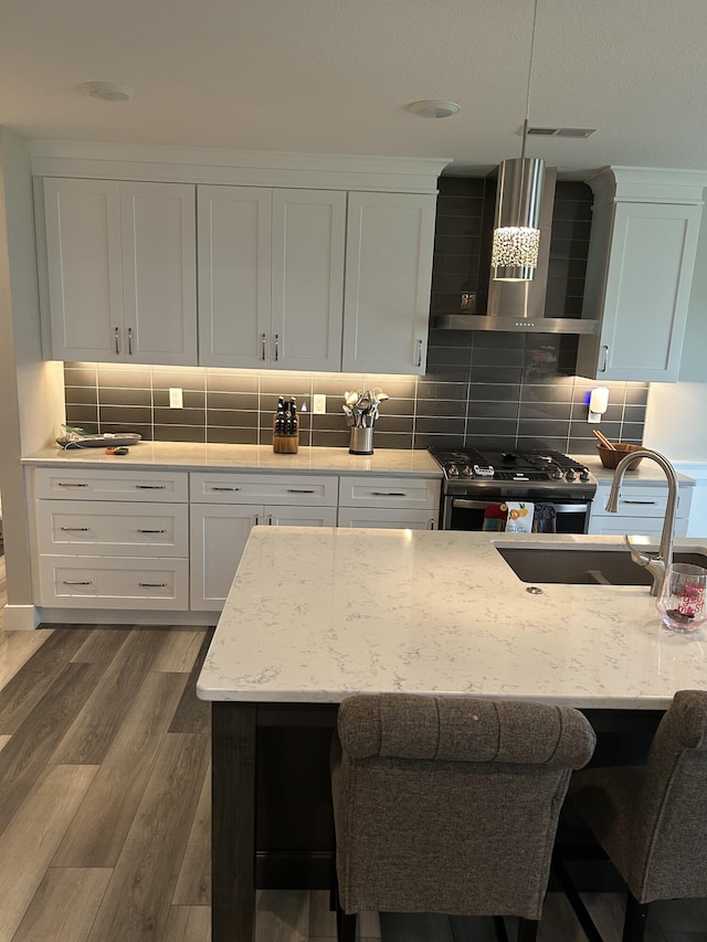 1001 Shore Acres Loop, Columbia, MO 65201 - kitchen featuring gas stove, wall chimney exhaust hood, a sink, a kitchen breakfast bar, and decorative backsplash
