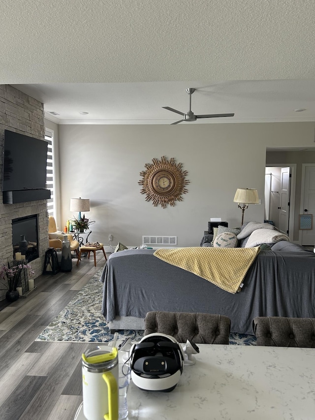 1001 Shore Acres Loop, Columbia, MO 65201 - bedroom featuring a fireplace, ornamental molding, wood finished floors, a textured ceiling, and a ceiling fan