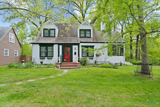 cape cod-style house with a front yard, roof with shingles, and brick siding