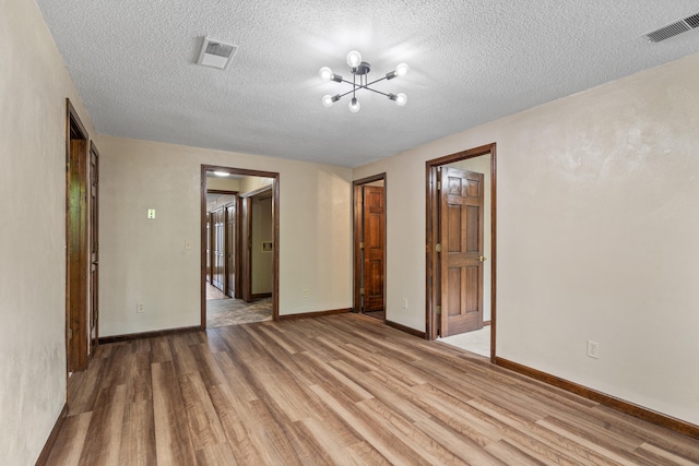 2036 Wendemere Ct, Jefferson City, MO 65109 - unfurnished room with light wood-style flooring, a chandelier, a textured ceiling, and baseboards