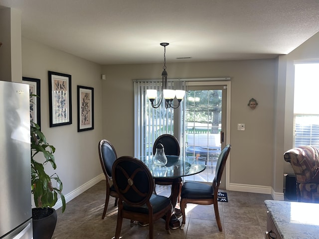 dining room with a chandelier, plenty of natural light, baseboards, and dark tile patterned floors
