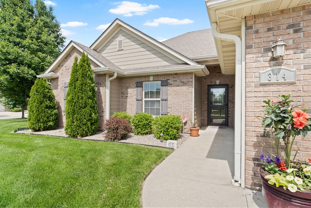 entrance to property with brick siding, roof with shingles, and a lawn